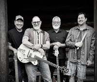 a black and white photo of a group of men with guitars